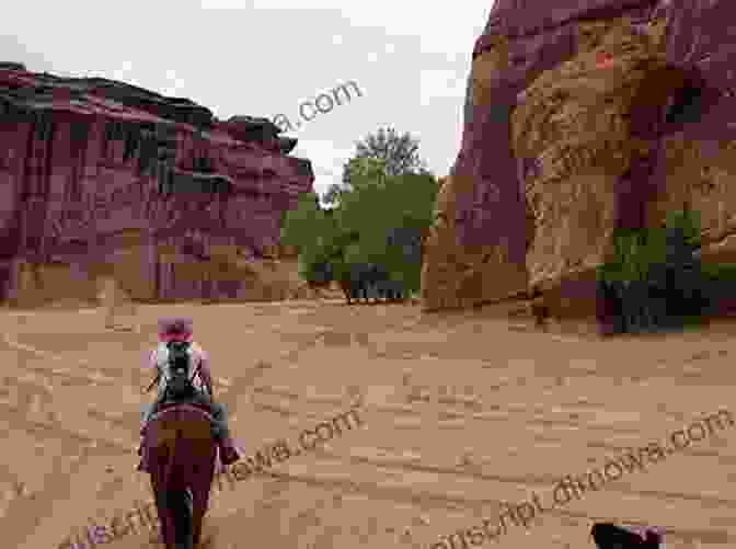 Chinle Miller Riding A Horse Through A Scenic Canyon, With Mountains In The Background Adventures With Horses Chinle Miller